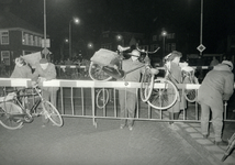 171079 Afbeelding van fietsers die hun fiets over de overwegbomen van de gesloten spoorwegovergang in de Schrans (?) te ...